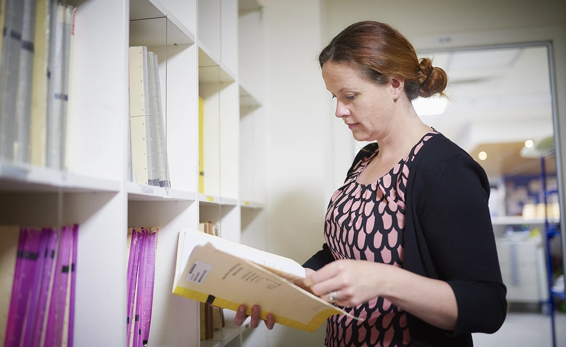 A researcher reviews clinical trial documents, ensuring meticulous data collection and adherence to protocols in perioperative medicine research.